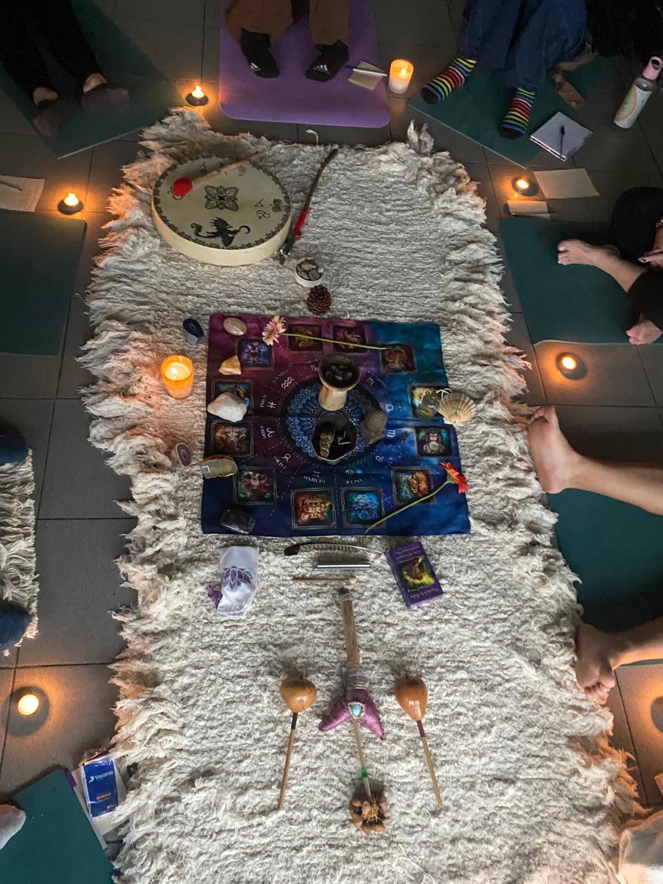 Rueda ritual con cartas, velas y personas alrededor
